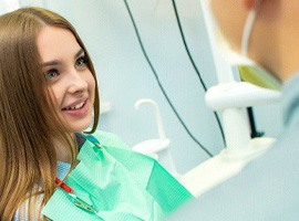 Girl in dental chair talking to her dentist