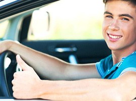 Young man in car giving thumbs up